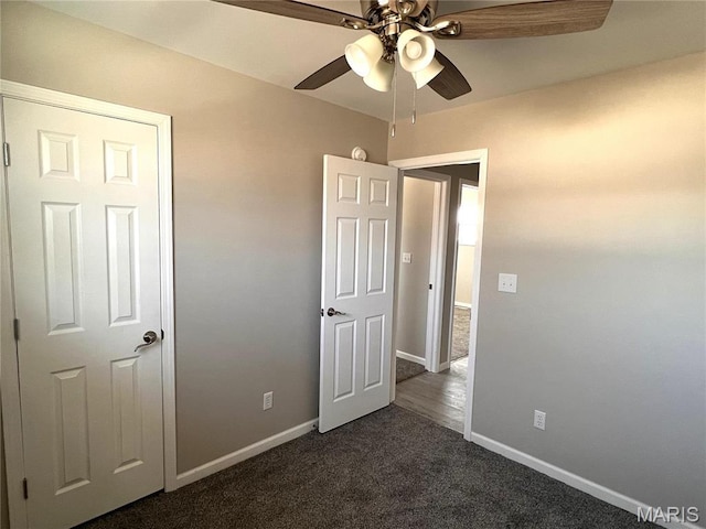 unfurnished bedroom featuring dark colored carpet, baseboards, and a ceiling fan
