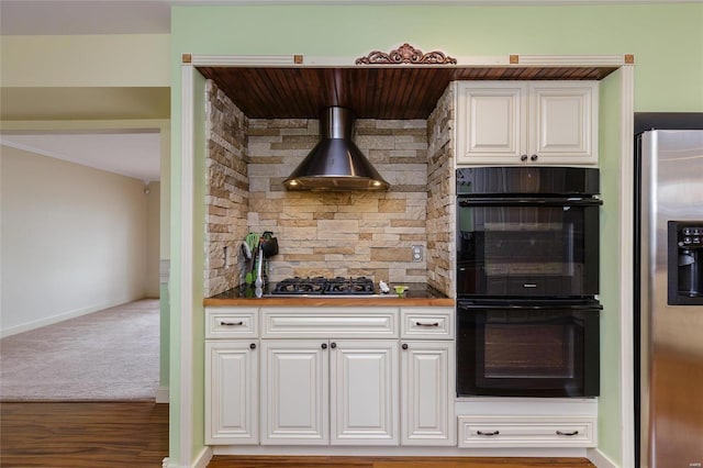 kitchen featuring appliances with stainless steel finishes, white cabinets, baseboards, wall chimney exhaust hood, and wood finished floors