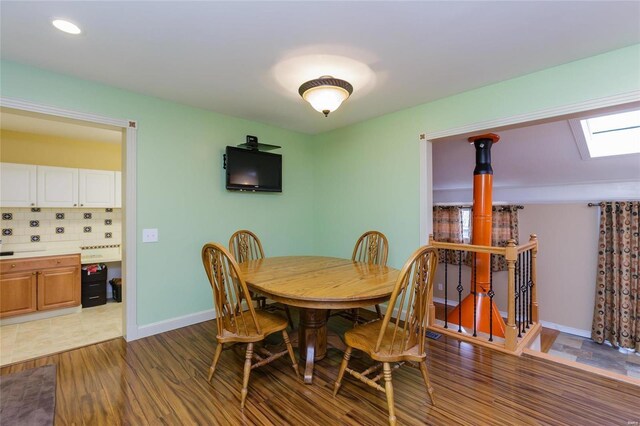 dining space with light wood finished floors, a skylight, baseboards, and recessed lighting