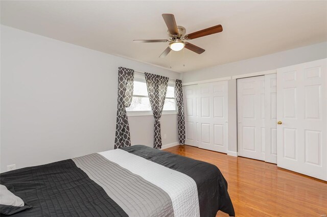 bedroom with two closets, light wood finished floors, and ceiling fan