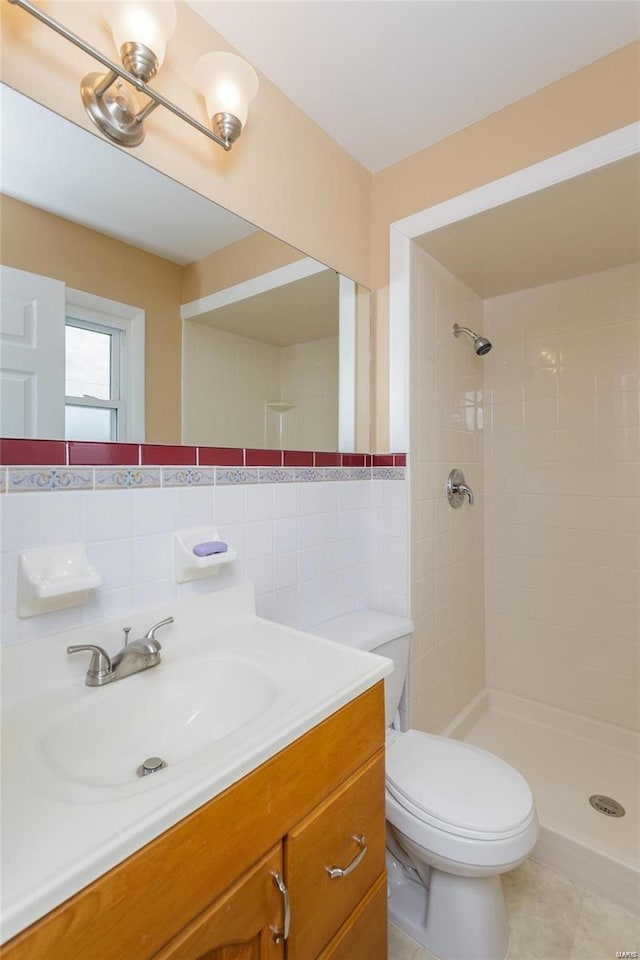 full bathroom featuring tiled shower, toilet, tile walls, vanity, and tile patterned floors