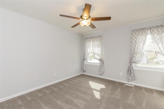 unfurnished room featuring a ceiling fan, healthy amount of natural light, carpet flooring, and baseboards