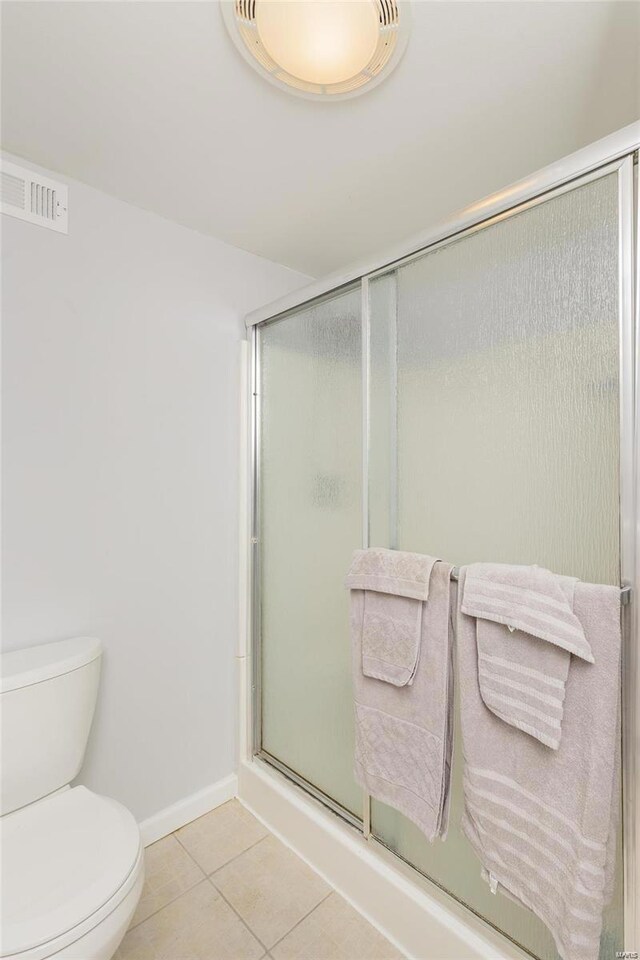 bathroom with tile patterned floors, an enclosed shower, toilet, and baseboards