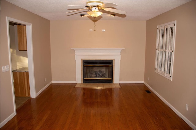 unfurnished living room featuring wood finished floors, a fireplace with flush hearth, a ceiling fan, a textured ceiling, and baseboards