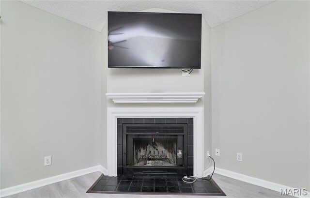 9167 Robin Ct, Saint Louis, MO 63144 - detailed view of wood finished floors, a fireplace with flush hearth, baseboards, and a textured ceiling