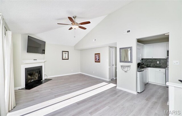 9167 Robin Ct, Saint Louis, MO 63144 - unfurnished living room with a ceiling fan, a fireplace with flush hearth, light wood-style floors, high vaulted ceiling, and baseboards