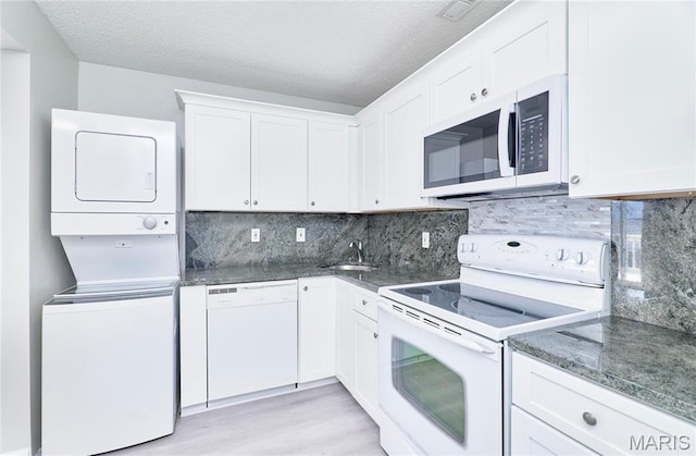 9167 Robin Ct, Saint Louis, MO 63144 - kitchen with white appliances, estacked washer and dryer, white cabinetry, light wood-style flooring, and a textured ceiling