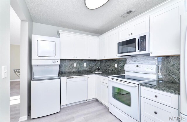 9167 Robin Ct, Saint Louis, MO 63144 - kitchen with white appliances, stacked washer / dryer, light wood finished floors, white cabinetry, and a textured ceiling