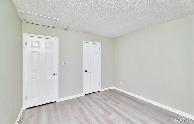 9167 Robin Ct, Saint Louis, MO 63144 - unfurnished bedroom featuring wood finished floors, attic access, baseboards, and a textured ceiling