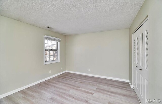9167 Robin Ct, Saint Louis, MO 63144 - unfurnished bedroom with light wood finished floors, a closet, a textured ceiling, and baseboards