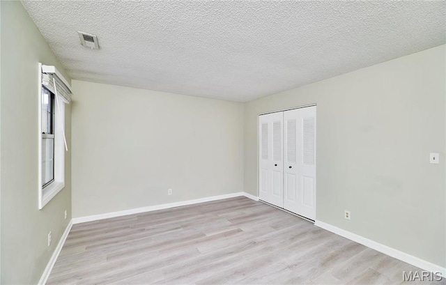 9167 Robin Ct, Saint Louis, MO 63144 - unfurnished bedroom with light wood finished floors, a closet, a textured ceiling, and baseboards