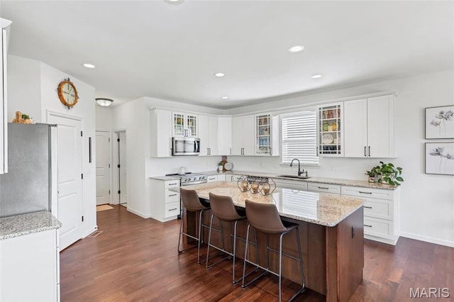 2 Wyndemere Ct, Lake St Louis, MO 63367 - kitchen featuring stainless steel microwave, a sink, a kitchen bar, dark wood-type flooring, and a kitchen island