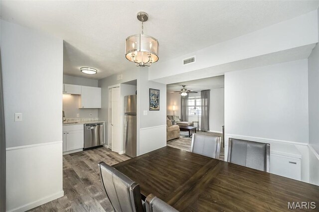 dining space featuring wood finished floors, ceiling fan, a chandelier, and baseboards