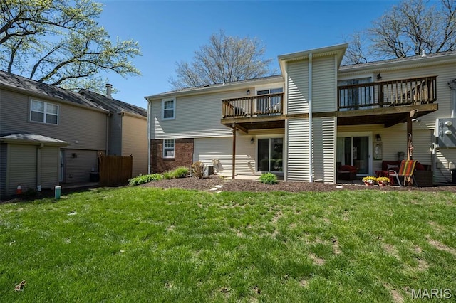 rear view of property featuring a lawn, a wooden deck, and brick siding