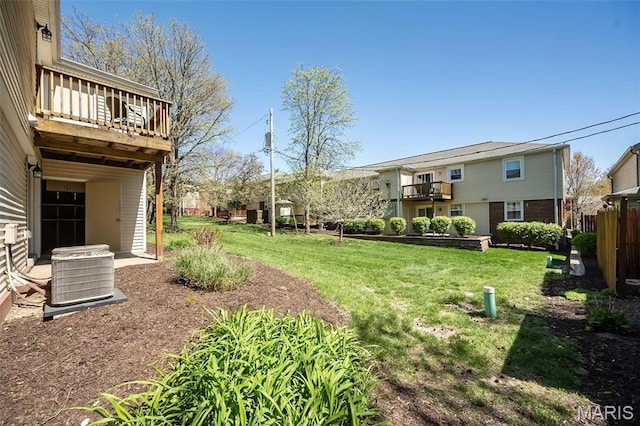 view of grassy yard with central air condition unit and a balcony