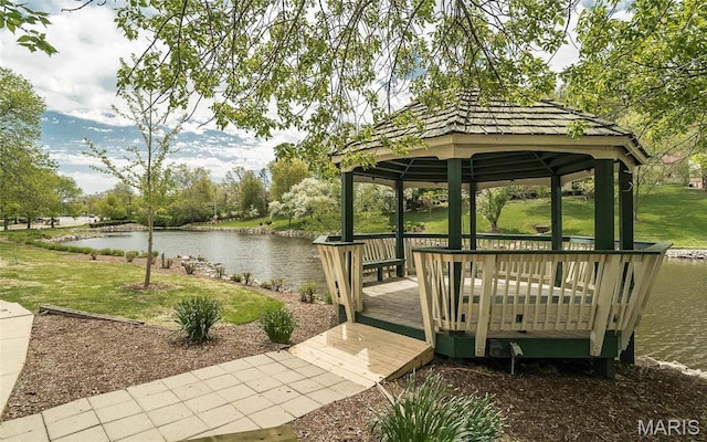 dock area with a gazebo, a water view, and a yard
