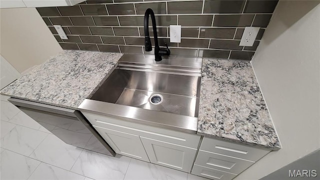 10216 Pannell Dr, Saint Louis, MO 63136 - kitchen view of a sink, tasteful backsplash, white cabinets, light stone counters, and dishwashing machine