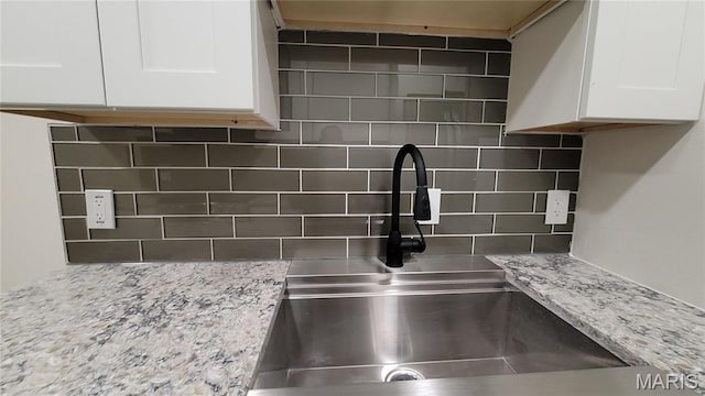 10216 Pannell Dr, Saint Louis, MO 63136 - kitchen view of a sink, backsplash, white cabinets, and light stone counters