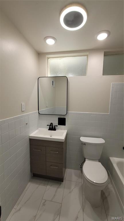 10216 Pannell Dr, Saint Louis, MO 63136 - full bath with tile walls, vanity, toilet, marble finish floors, and a tub to relax in