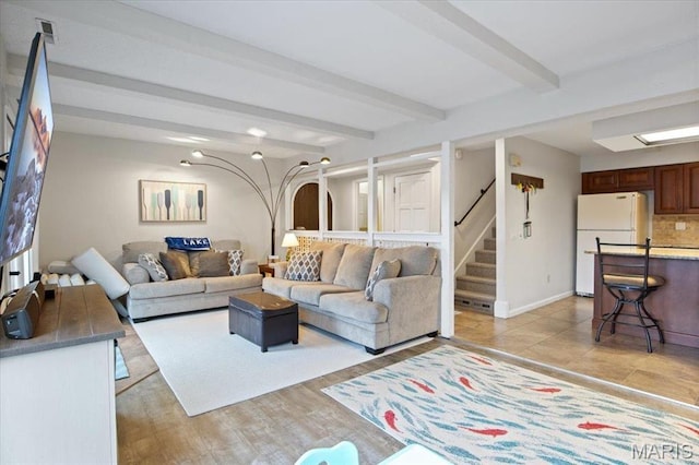 living room with stairs, beamed ceiling, and baseboards