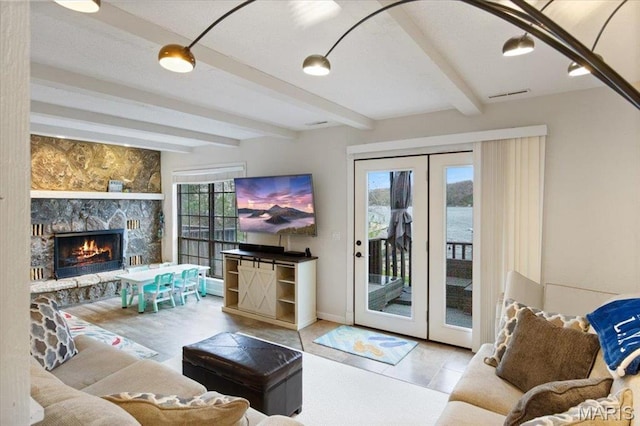 living room featuring beamed ceiling, a fireplace, baseboards, and french doors