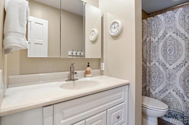 bathroom featuring toilet, vanity, and curtained shower