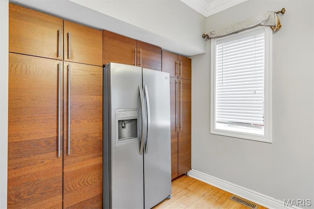 7415 Wellington Ave, Saint Louis, MO 63130 - kitchen with stainless steel fridge with ice dispenser, light wood-style floors, plenty of natural light, ornamental molding, and brown cabinets