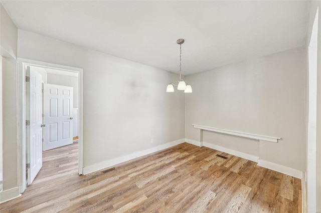 7001 Plymouth Ave, Saint Louis, MO 63130 - unfurnished dining area with a chandelier, light wood-style flooring, and baseboards