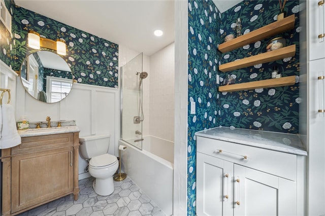 full bathroom with wallpapered walls, vanity, toilet, wainscoting, and tile patterned floors