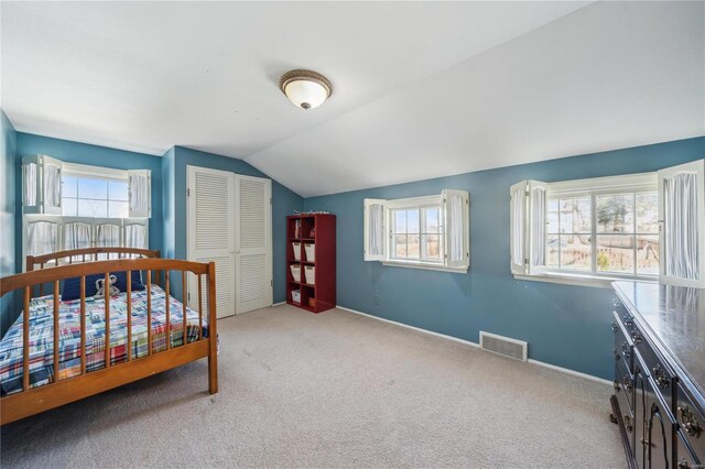 bedroom with a closet, carpet flooring, lofted ceiling, and baseboards
