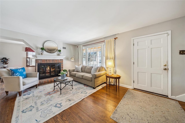 living area featuring a brick fireplace, wood finished floors, and baseboards