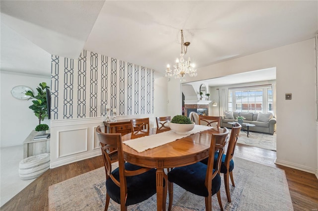 dining space featuring a chandelier, wood finished floors, and wainscoting