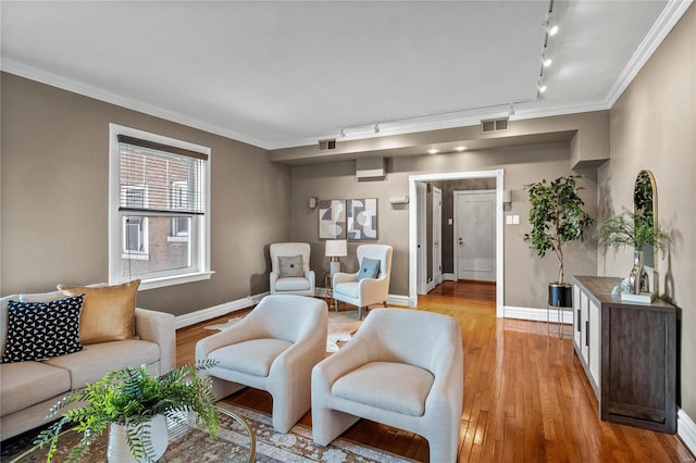living area featuring rail lighting, baseboards, light wood finished floors, and ornamental molding