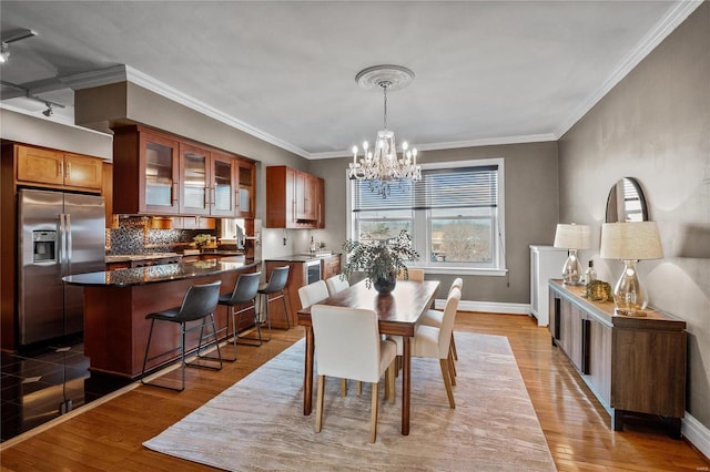 dining area with a chandelier, wood finished floors, baseboards, and crown molding