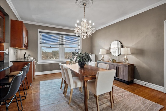 dining space featuring a chandelier, baseboards, wood finished floors, and crown molding