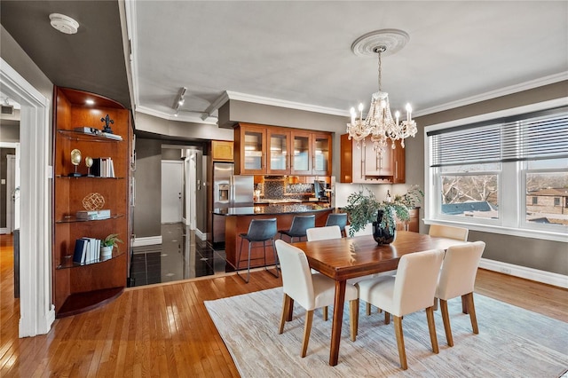 dining room featuring ornamental molding, a chandelier, wood-type flooring, and baseboards