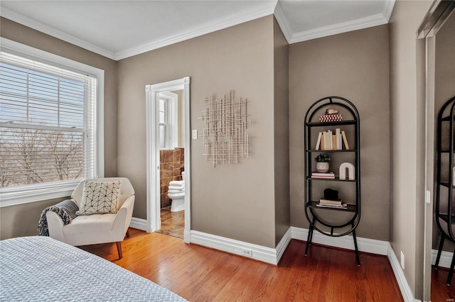 bedroom with wood finished floors, baseboards, crown molding, and connected bathroom