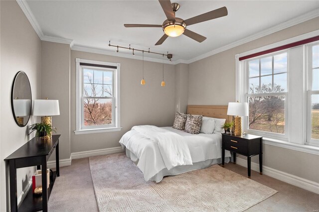 carpeted bedroom featuring baseboards, rail lighting, ornamental molding, and ceiling fan