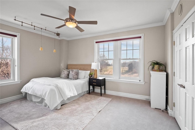 bedroom featuring multiple windows, crown molding, light colored carpet, baseboards, and a ceiling fan