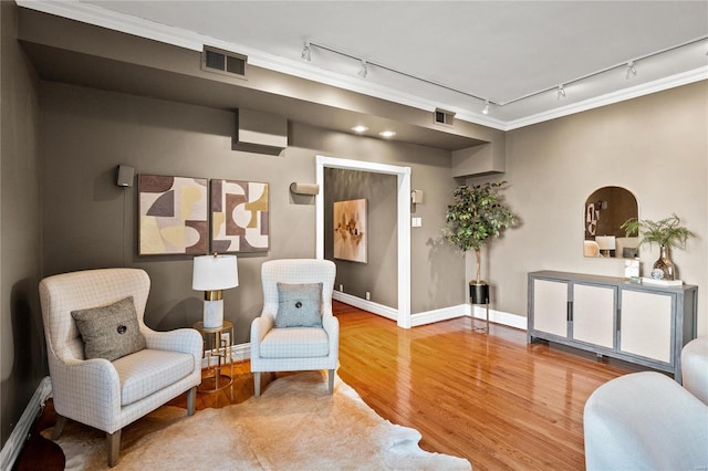 sitting room with rail lighting, baseboards, wood finished floors, and ornamental molding
