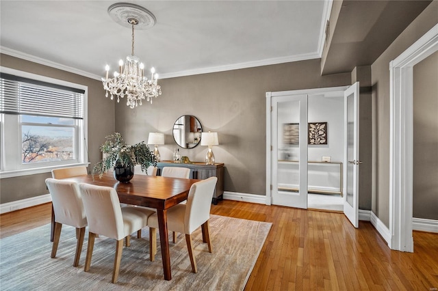 dining room featuring a chandelier, baseboards, hardwood / wood-style floors, and ornamental molding