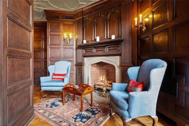 living area featuring wooden walls and a lit fireplace
