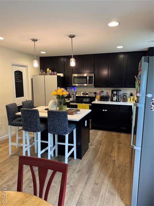 757 Fox Creek Dr, Fenton, MO 63026 - kitchen with stainless steel appliances, dark cabinets, light countertops, a kitchen island, and light wood-type flooring