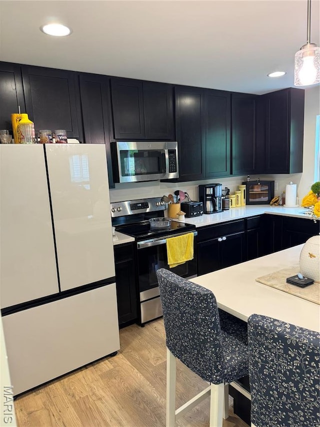 757 Fox Creek Dr, Fenton, MO 63026 - kitchen featuring stainless steel appliances, dark cabinets, light countertops, light wood-style floors, and recessed lighting