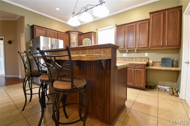 102 W High St, Troy, IL 62294 - kitchen featuring light tile patterned floors, a kitchen bar, crown molding, pendant lighting, and glass insert cabinets