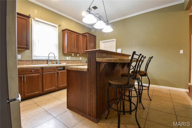 102 W High St, Troy, IL 62294 - kitchen with light tile patterned floors, a sink, a breakfast bar area, crown molding, and pendant lighting