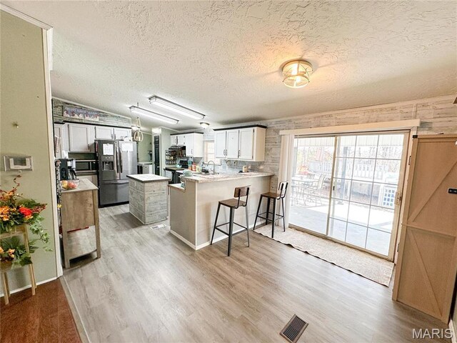 405 County Road 5015, Salem, MO 65560 - kitchen featuring stainless steel appliances, a textured ceiling, a peninsula, light wood-type flooring, and light countertops