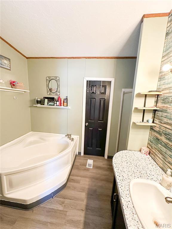 405 County Road 5015, Salem, MO 65560 - full bathroom featuring ornamental molding, wood finished floors, a garden tub, vanity, and a stall shower