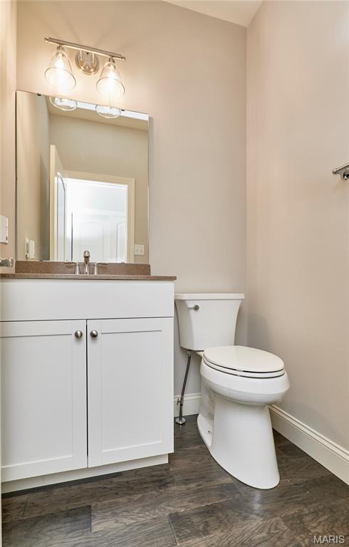 513 Upper Ridgepointe Ct, Lake St Louis, MO 63367 - half bath featuring baseboards, toilet, wood finished floors, and vanity