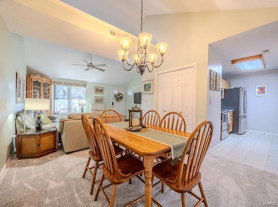 dining space with lofted ceiling, light carpet, a chandelier, a ceiling fan, and baseboards